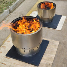 Load image into Gallery viewer, Two smokeless metal fire pits with flames on a concrete surface.