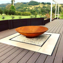 Load image into Gallery viewer, Rust-colored cast iron fire pit on a wooden deck with a scenic background
