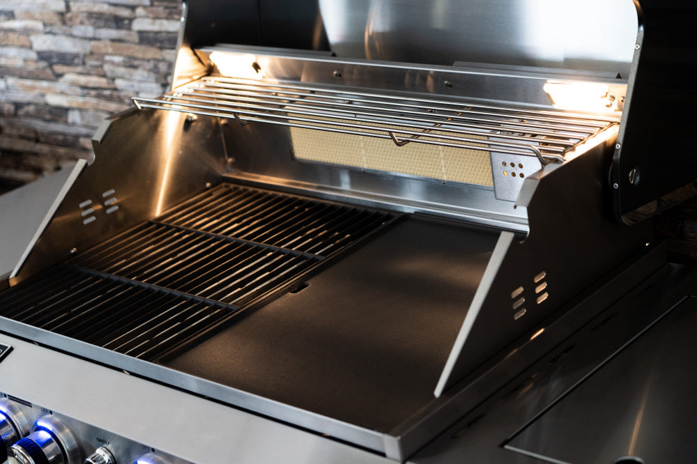 Stainless steel BBQ with open lid showing grill and interior components against a stone wall background