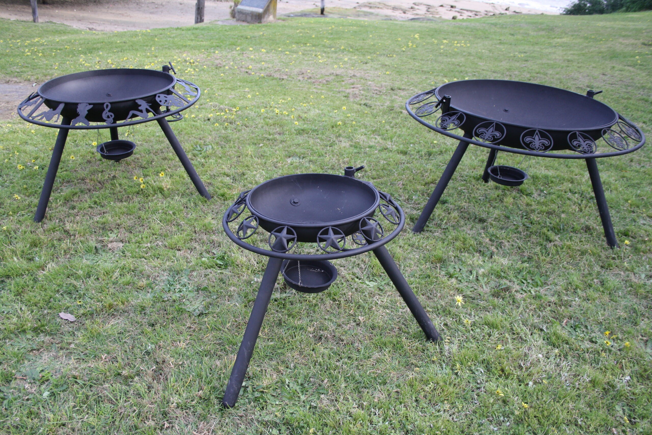 Three black metal bbq / fire pits on grass
