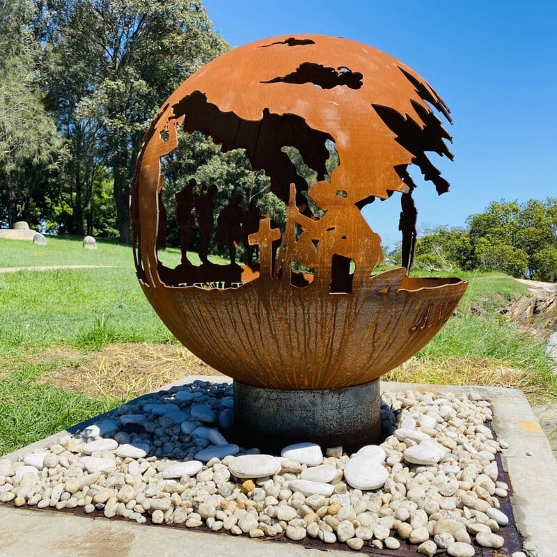 Decorative fire pit sphere with ANZACs design in a garden setting