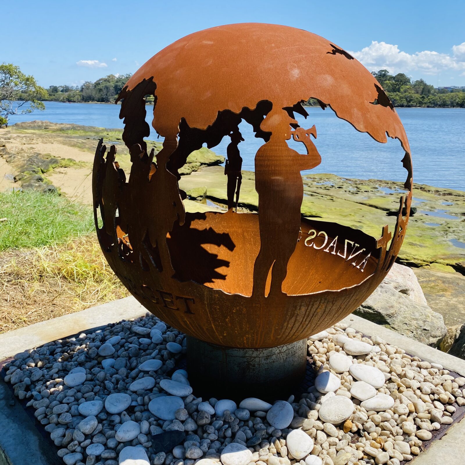 Decorative fire pit sphere with ANZACs design in a garden setting