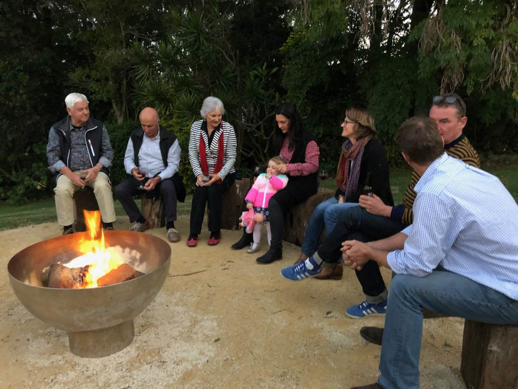 Group of people sitting around a fire pit in an outdoor setting