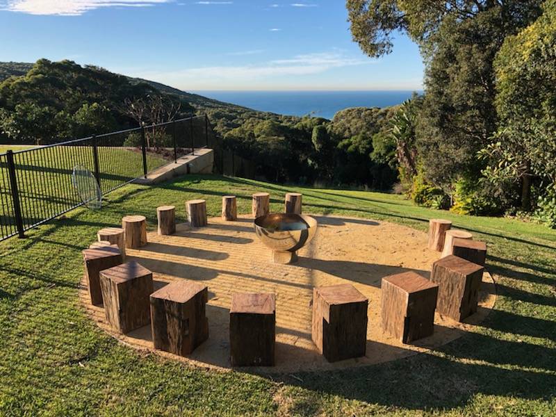 Wooden fire pit area with ocean view in the background
