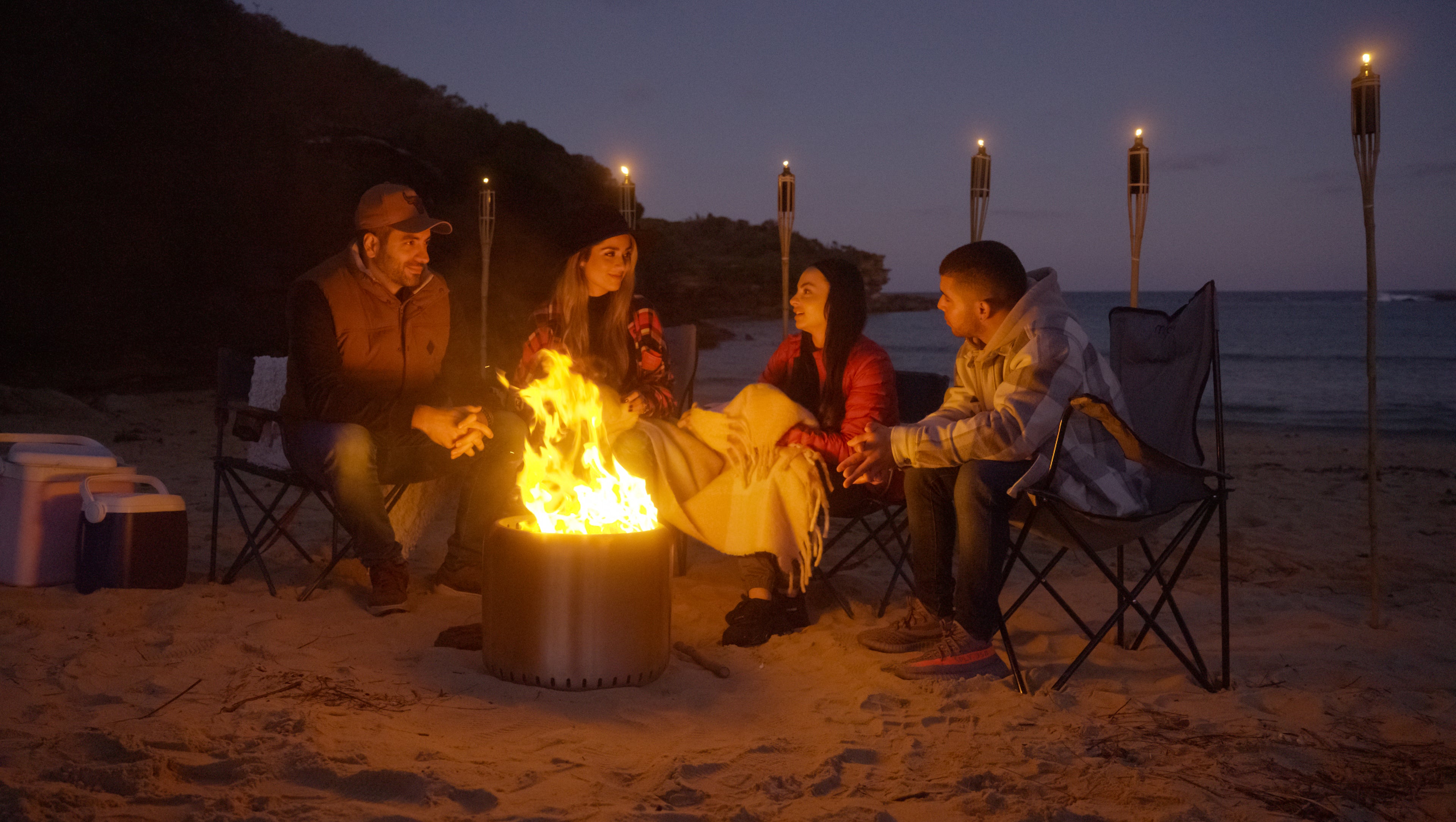 People gathering around the Ecoflame Smokeless fire pit on the beach