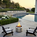Outdoor setting with a Ecoflame smokeless fire pit, chairs, and pool in the background