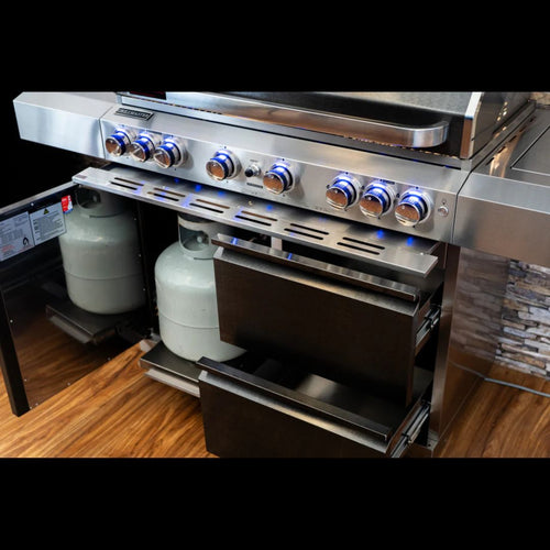 Stainless steel gas grill with propane tanks on a wooden floor.